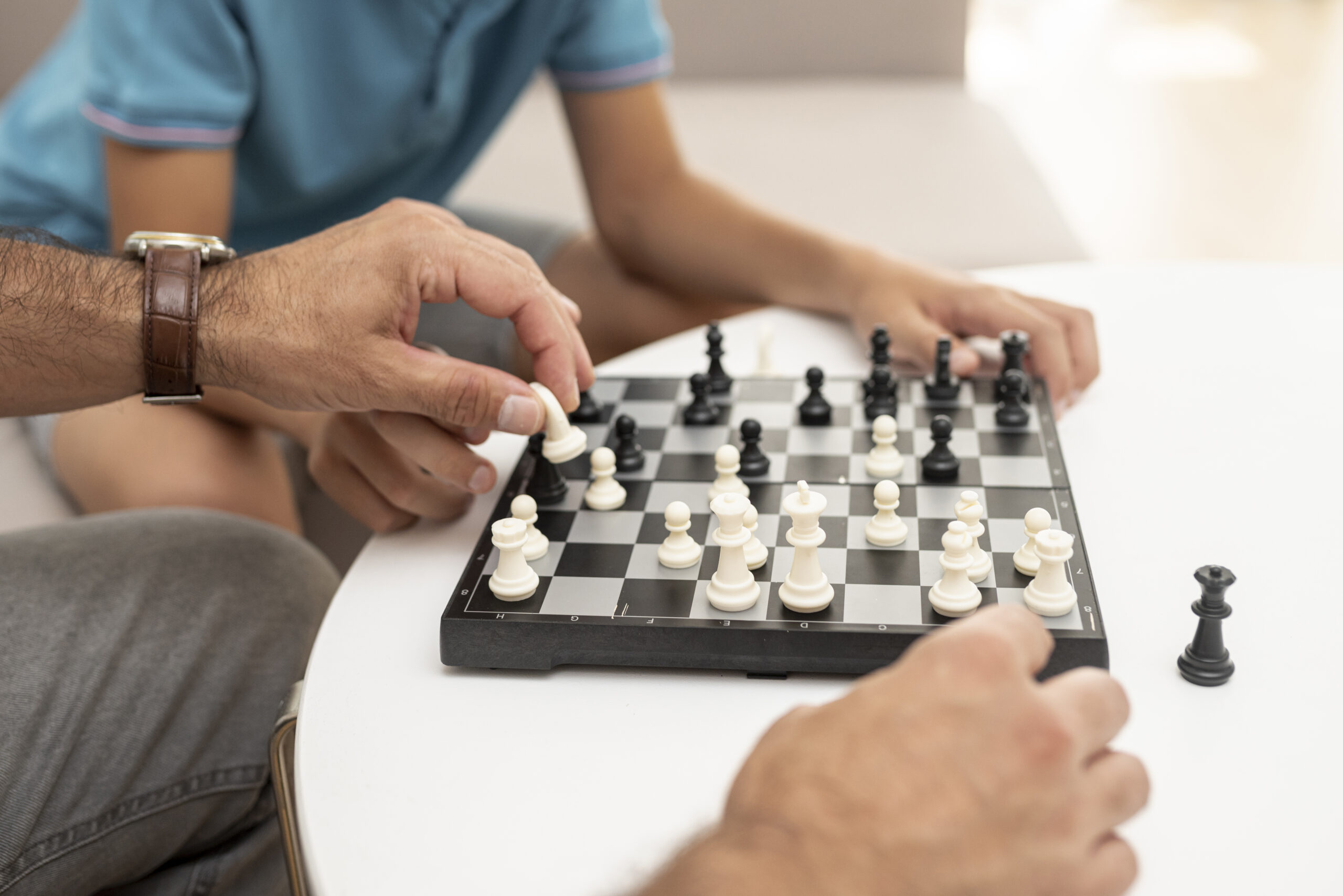 Niño y Adulto juegan al ajedrez, un juego de estrategia.